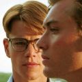 a man in glasses looks at another man