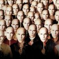 a crowd of people holding John Malkovich paper masks in front of their faces