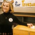 a highschool student puts a vote into a locked wooden box
