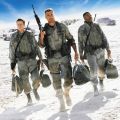 three men dressed in army fatigues walking in the desert