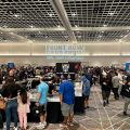 a crowd of people shopping at booths featuring cards and collectibles 
