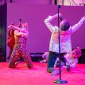 people dancing and singing on a stage 