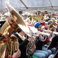 a large crowd of people playing tubas and brass instruments