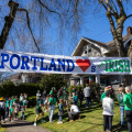 a crowd of people standing under a Portland Loves the Irish banner