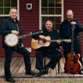 three people post with 2 guitars and a banjo