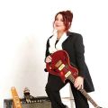 woman with a guitar sitting next to an amp