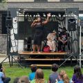 a woman on a portable stage sings into a microphone to a crowd of children 