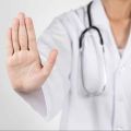 person wearing lab coat and stethoscope holding up hand