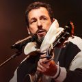 man playing a guitar and singing into a microphone