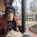 a person drinking coffee at a table in a coffee shop