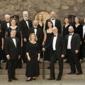 a choir standing on the steps in front of a stone church