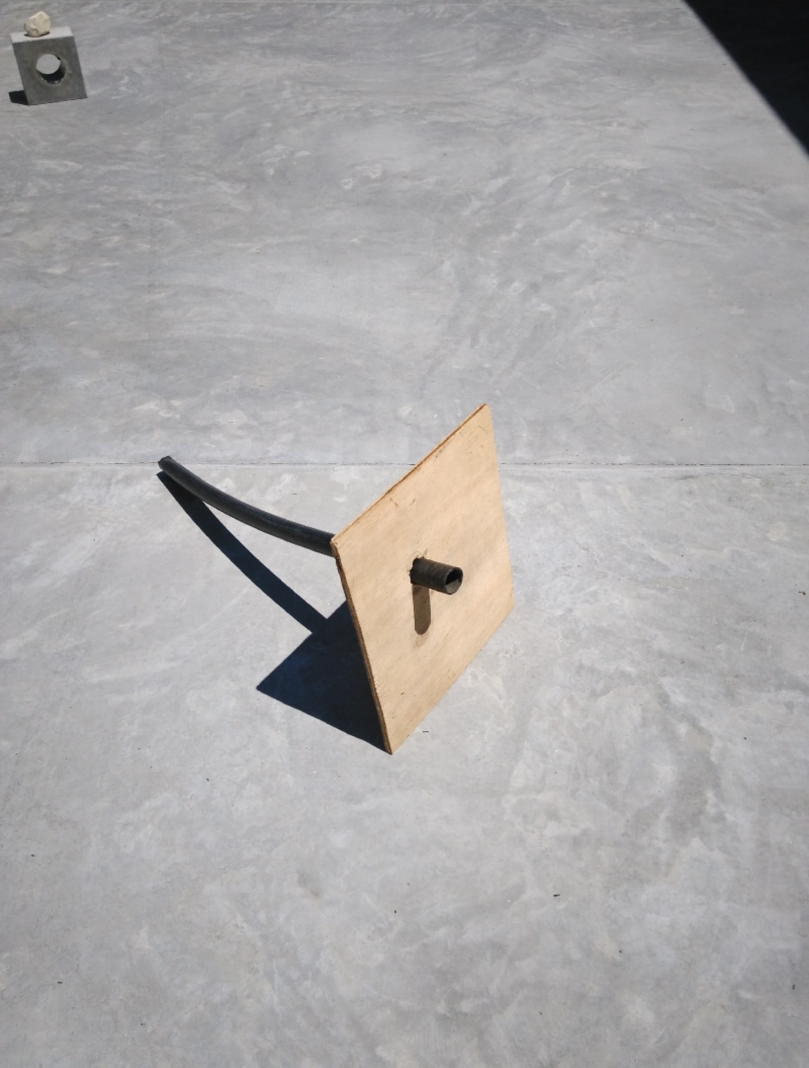 if it fits - in casa wabi, a black tube is exactly the size of a hole in a wood board, therefore it is in the hole and it holds the wood board - PET black tube, plywood - paul lahana