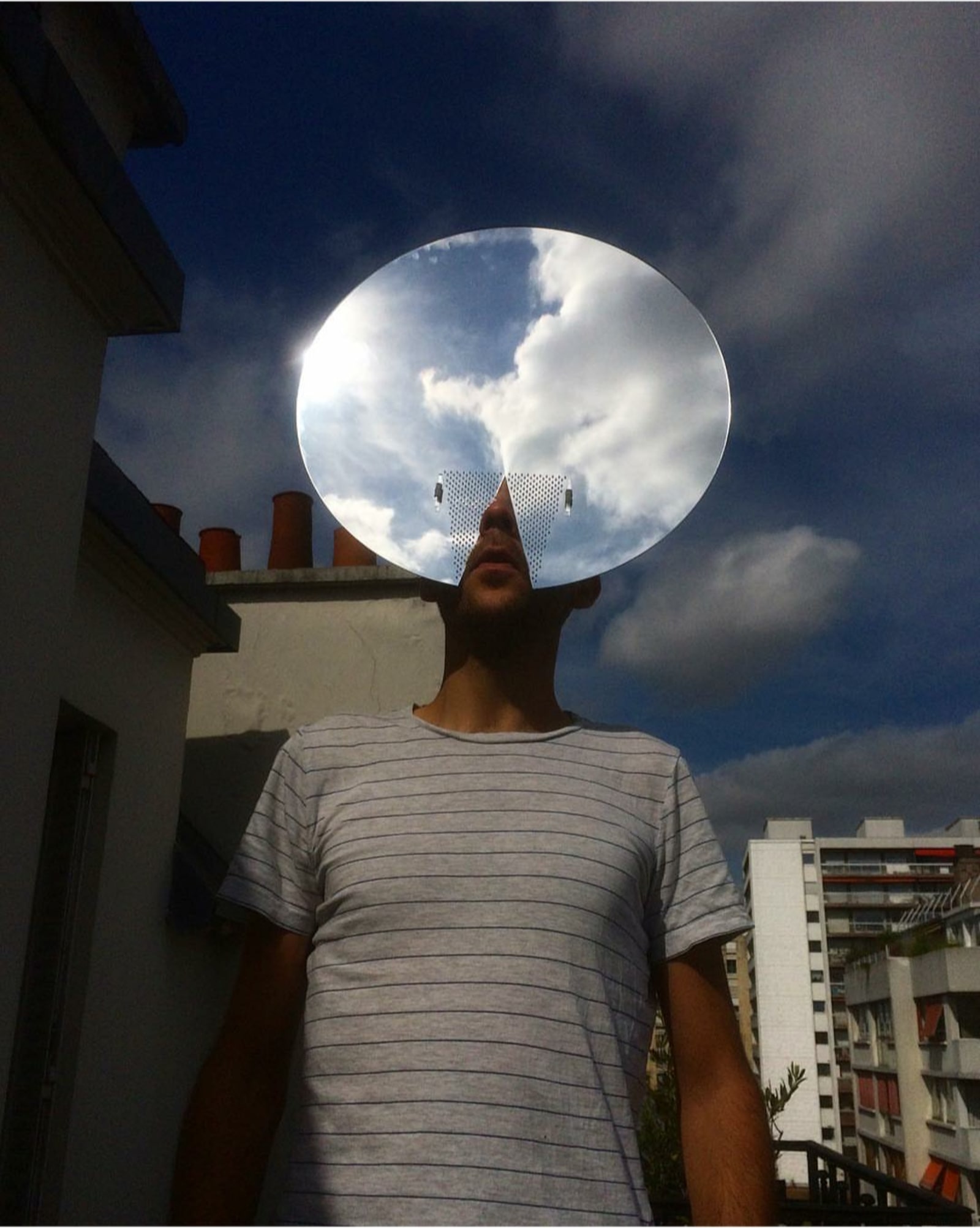 looking for gods - a round mirror face mask is on a face and is mirroring the cloudy sky - mirror plexiglass, sky - paul lahana