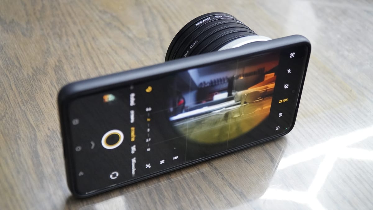 ภาพ Phone on the table แสดงโทรศัพท์พร้อมอุปกรณ์เลนส์บนโต๊ะไม้