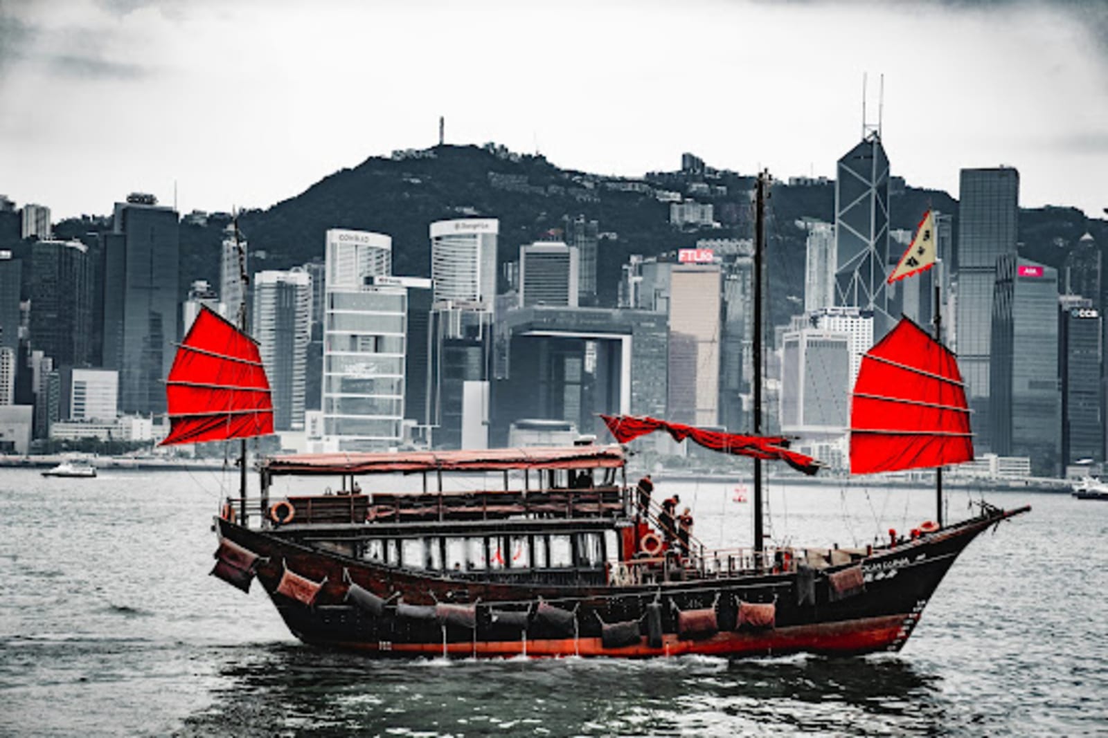 Boat cruising on the waters of Hong Kong with the city’s skyscrapers in the background