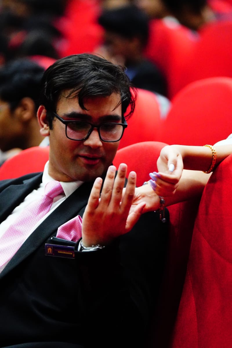 Founder, Mr Harsh Malhotra in formal blazer and pink tie seated in the Delhi MUN 1.0 opening ceremony audience