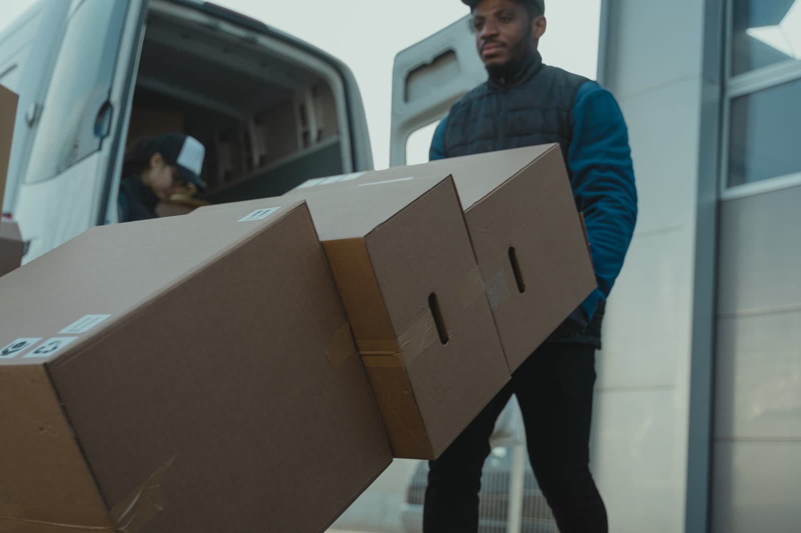 Livreur portant des cartons devant un fourgon utilitaire