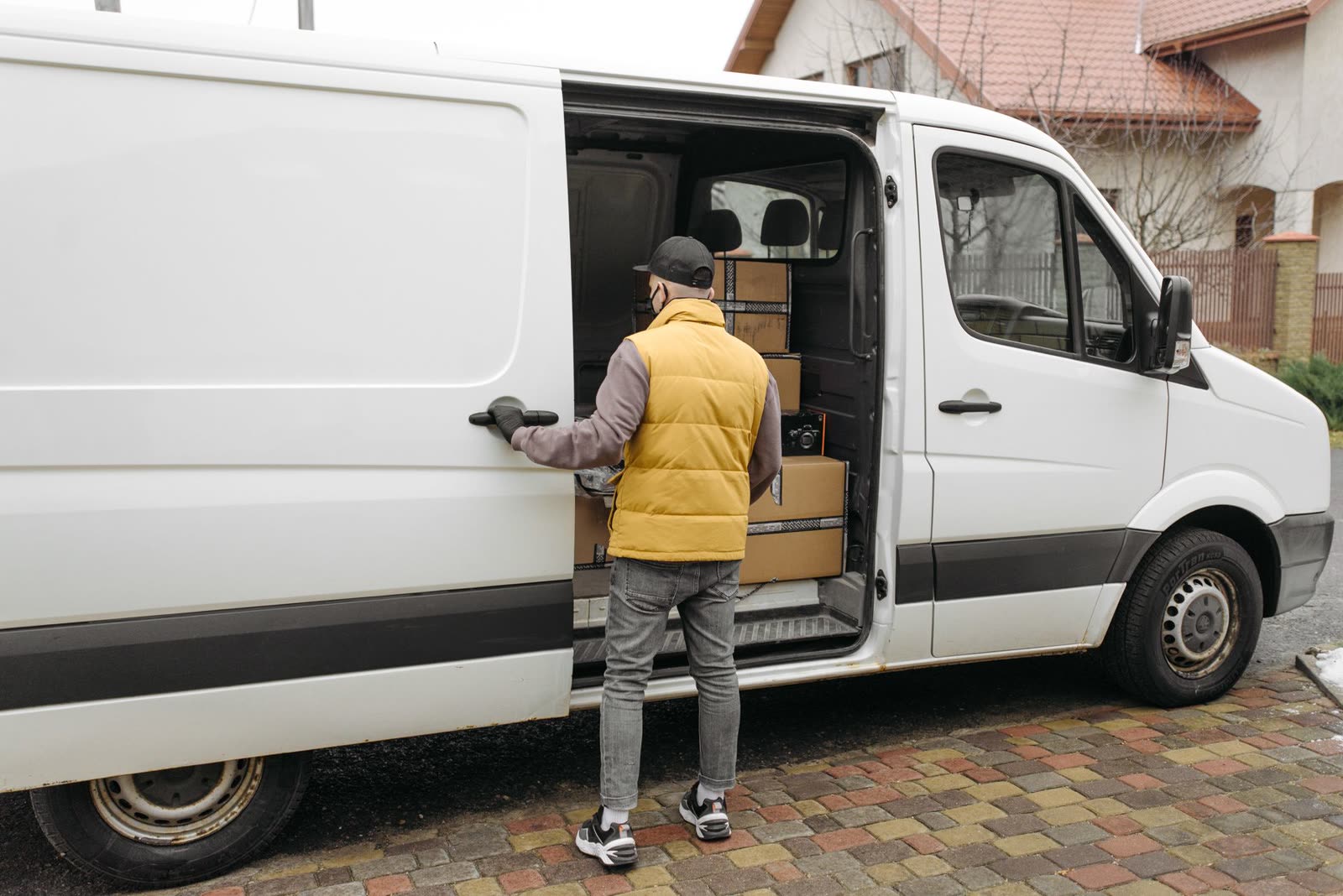 Livreur chargeant des cartons par la porte latérale d'un fourgon utilitaire blanc