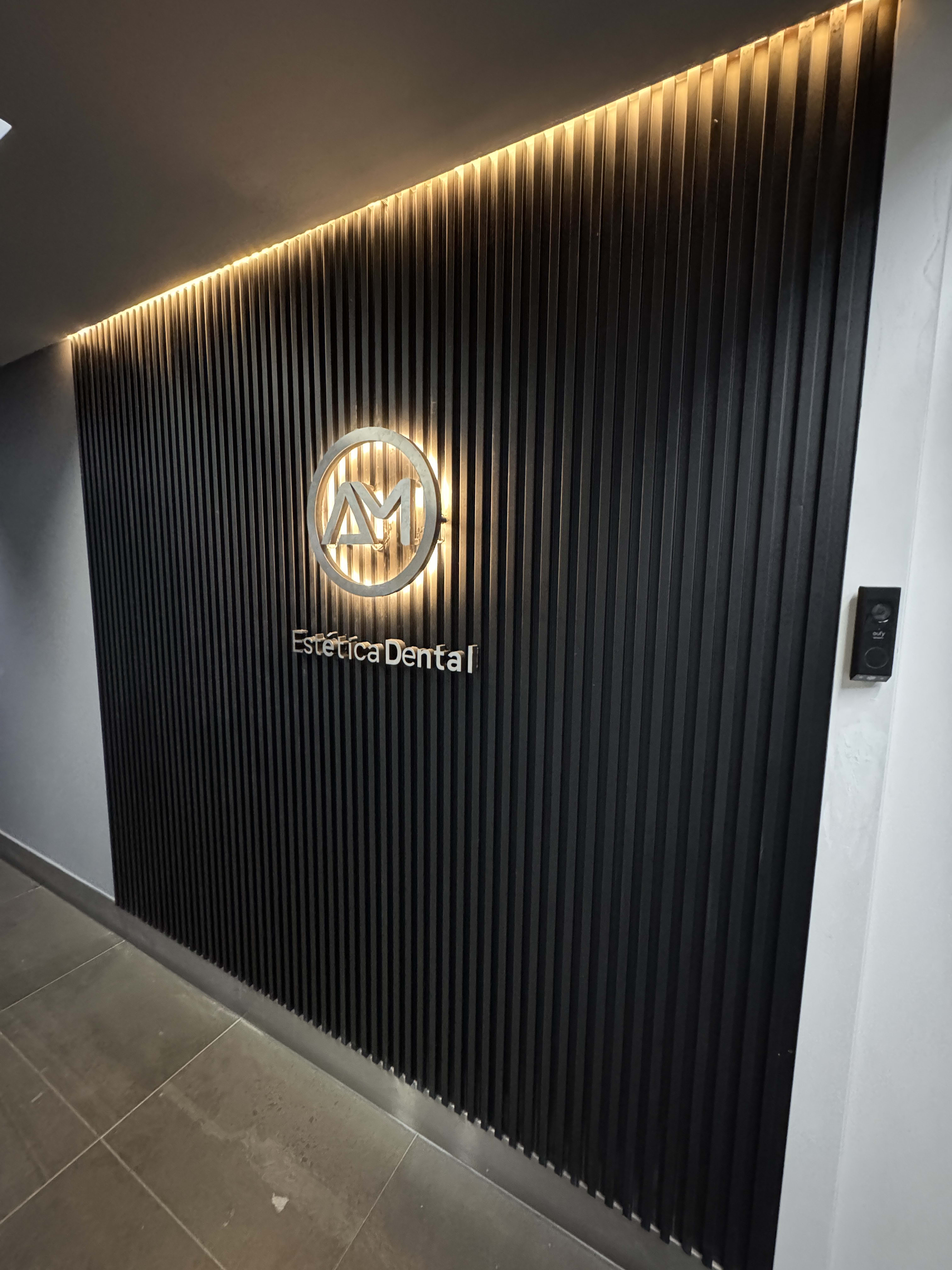 Entrada principal de AM Estética Dental con el logotipo iluminado en Puerto Madero