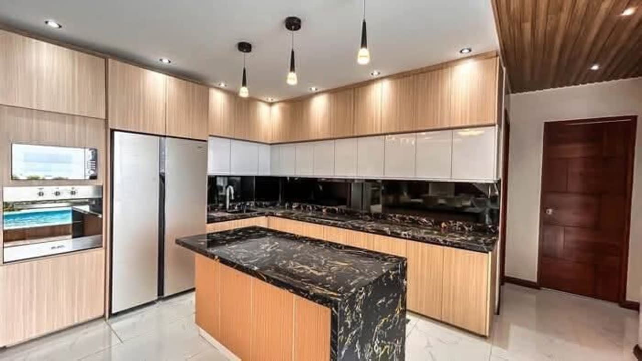 Modern kitchen with black countertops and wood cabinets in luxury Cebu home