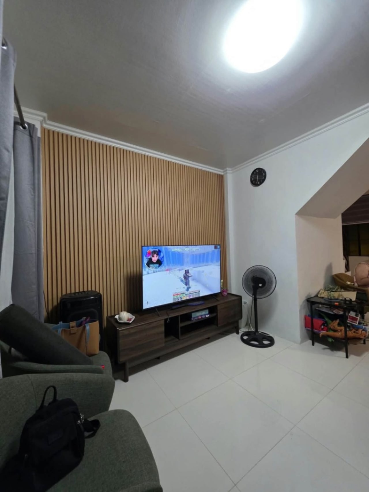 Wide view of the living room with TV and black panels at the back in house and lot for sale in Tisa