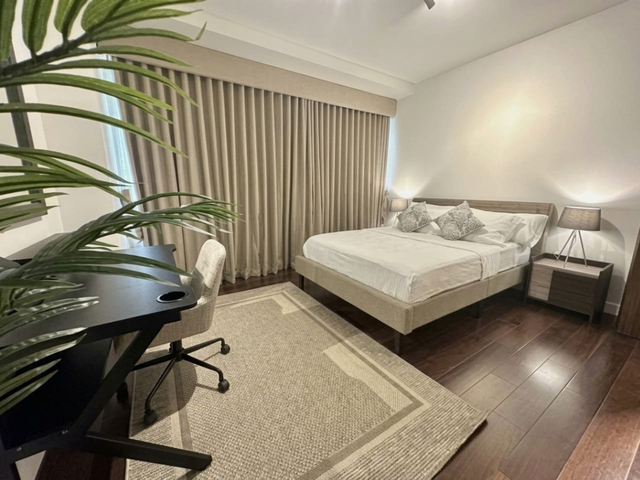 Fully furnished bedroom with king-size bed, work desk and curtains at The Alcoves Cebu condo