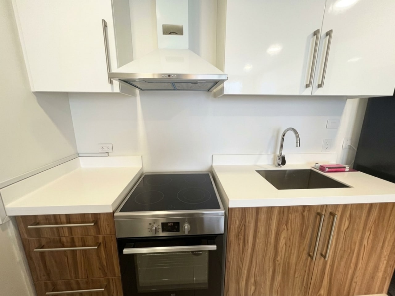 Modern kitchen with built-in cabinets, induction stove, range hood and sink in The Alcoves Cebu condo