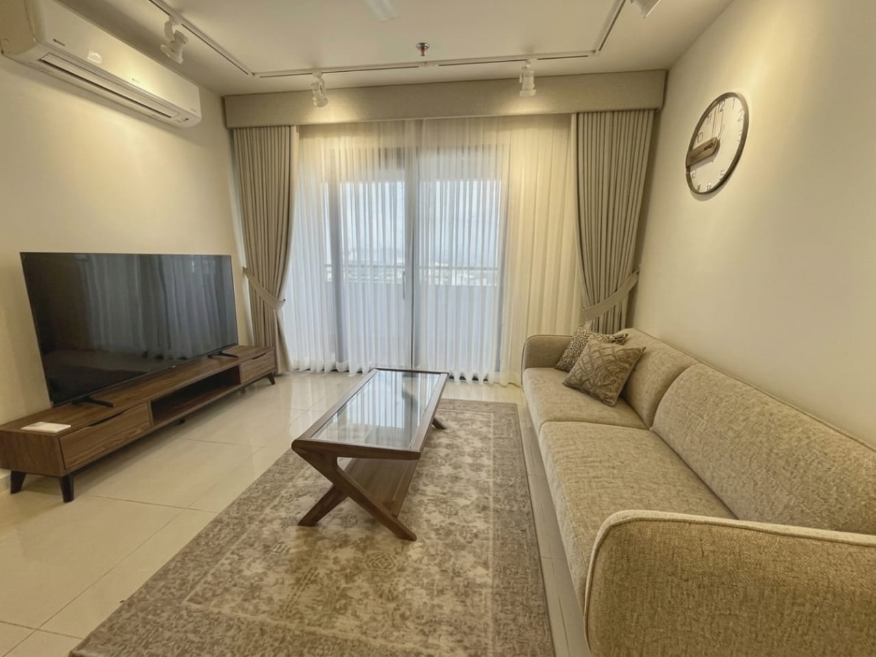 Furnished living room with television, sofa and large windows in 1-bedroom condo for sale at The Alcoves Cebu