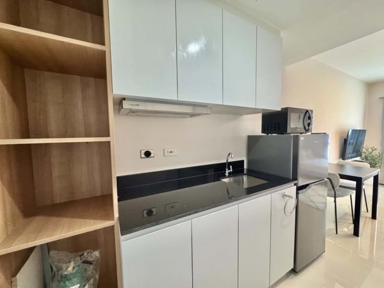 Modern kitchen with white cabinets, range hood, refrigerator and microwave in JTower Residences studio Mandaue