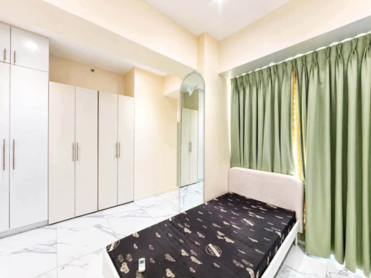 Bedroom with floor-to-ceiling white closets, green drapes and single bed in Cebu City luxury condo