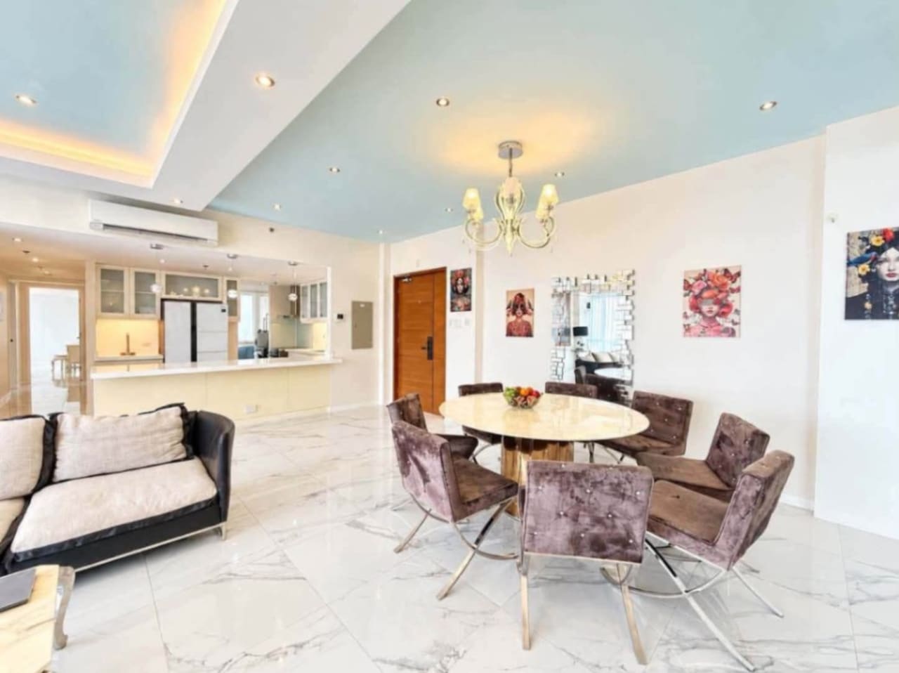 Dining area with round marble table and velvet chairs beside the kitchen in a 144 sqm Marco Polo condo