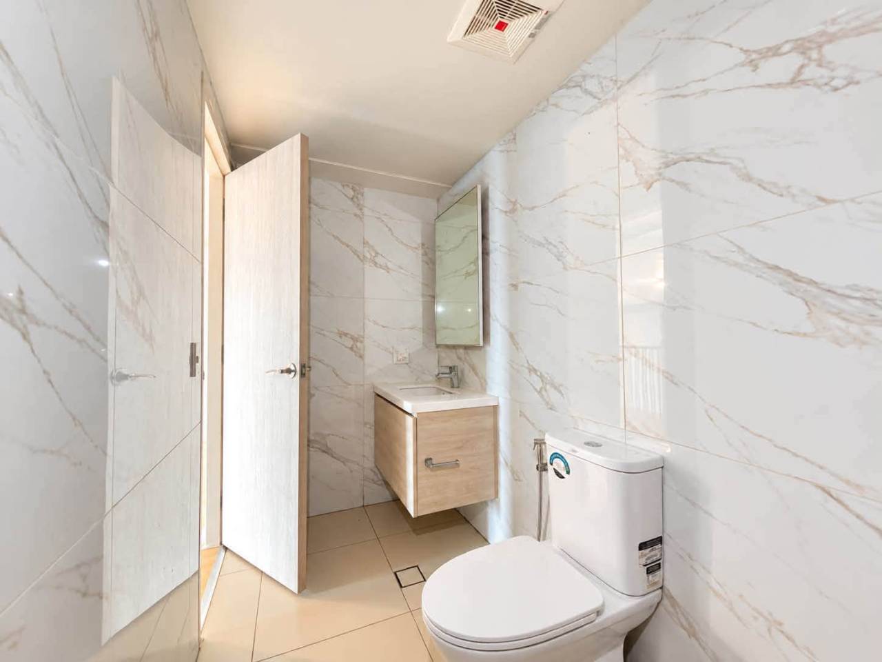 Bright bathroom interior with vanity, toilet and tiled walls in a Mandani Bay Tower 2 condo for sale
