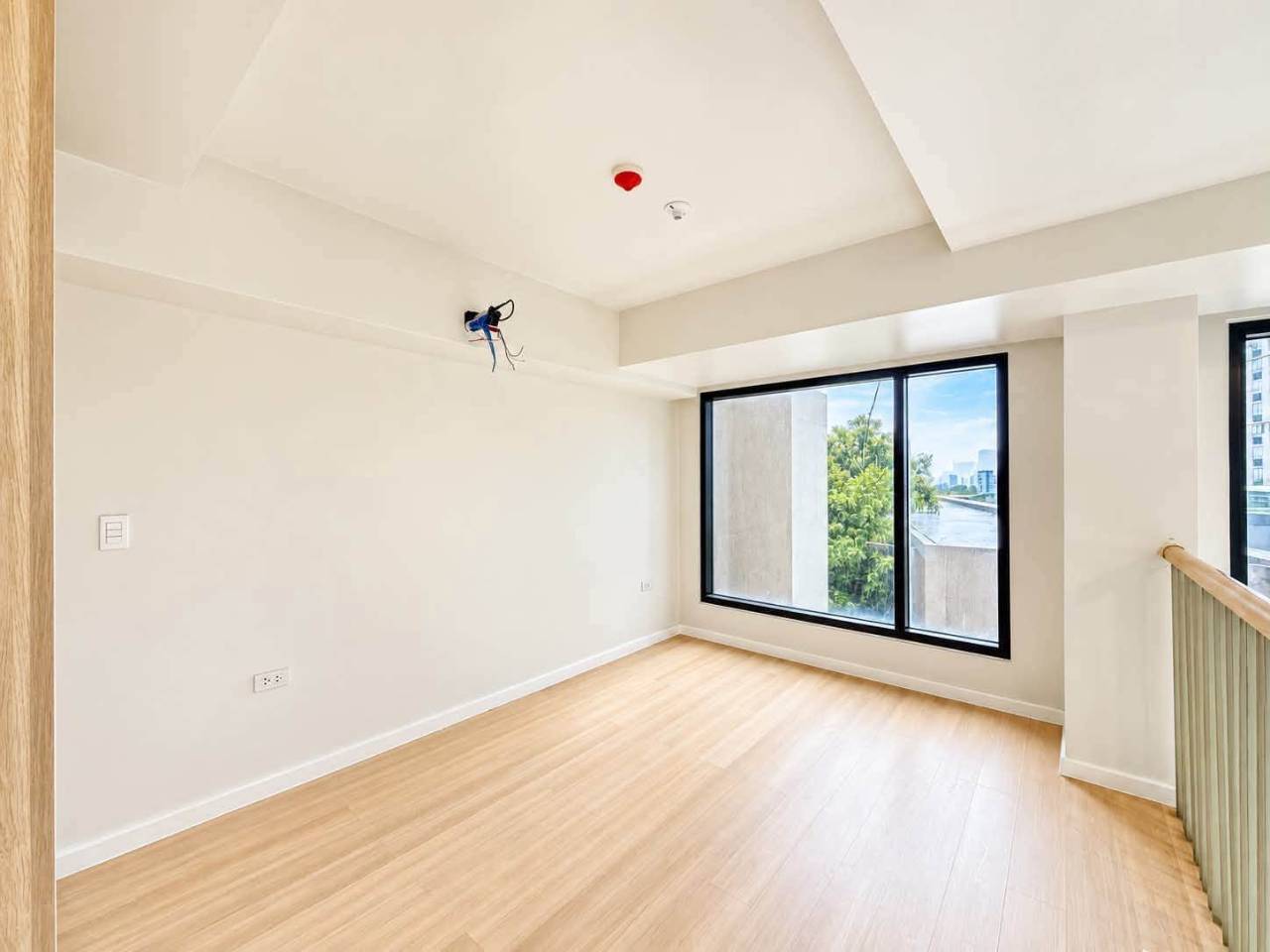 Bright upper-level loft room with wood flooring and large windows in a Mandani Bay Tower 2 condo