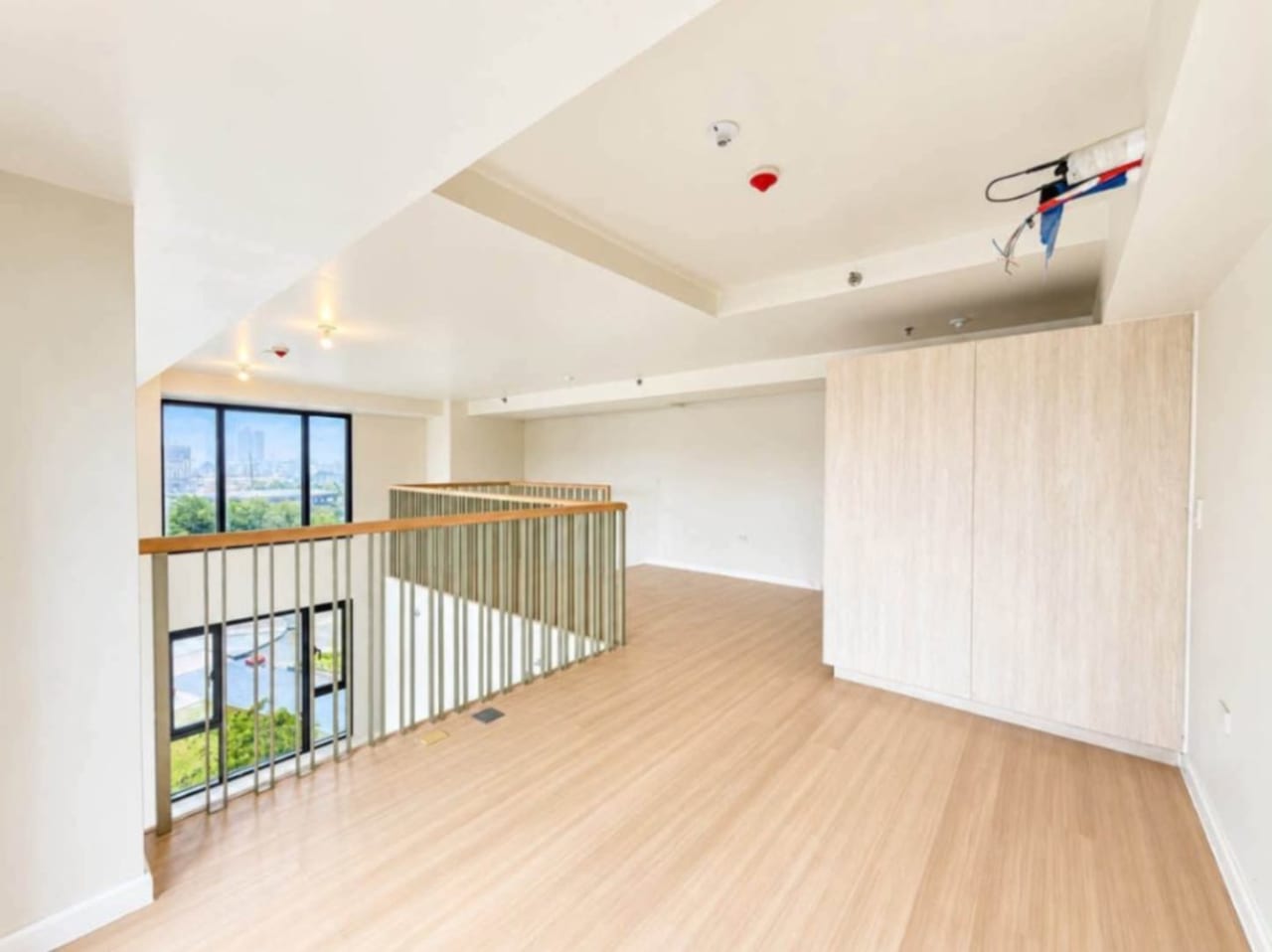 Open mezzanine area with black metal railing and tall windows in a Mandani Bay loft condominium