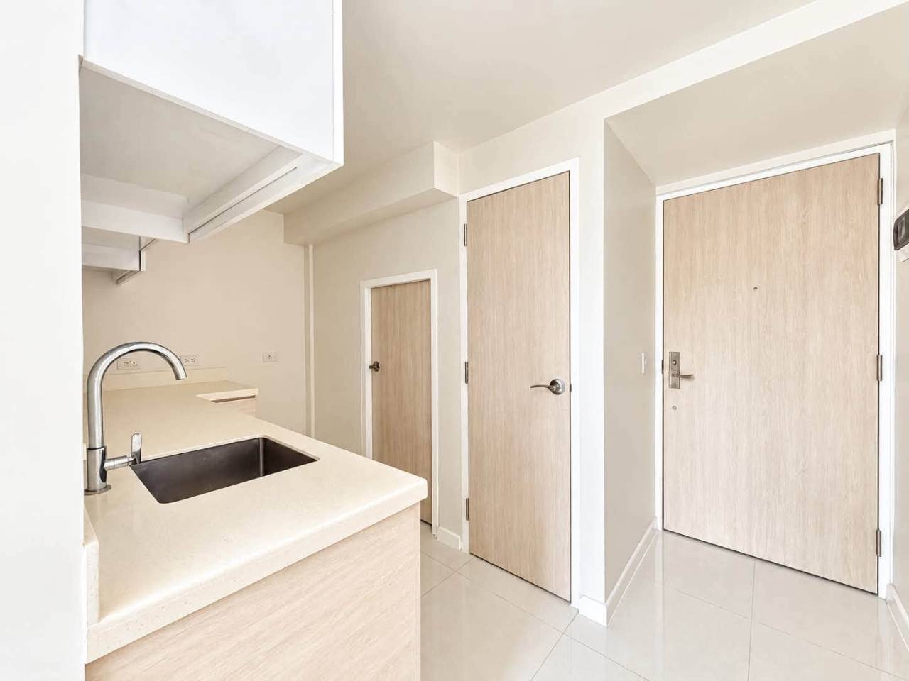 Compact modern kitchen with white cabinets and countertop in a Mandani Bay Tower 2 loft condo