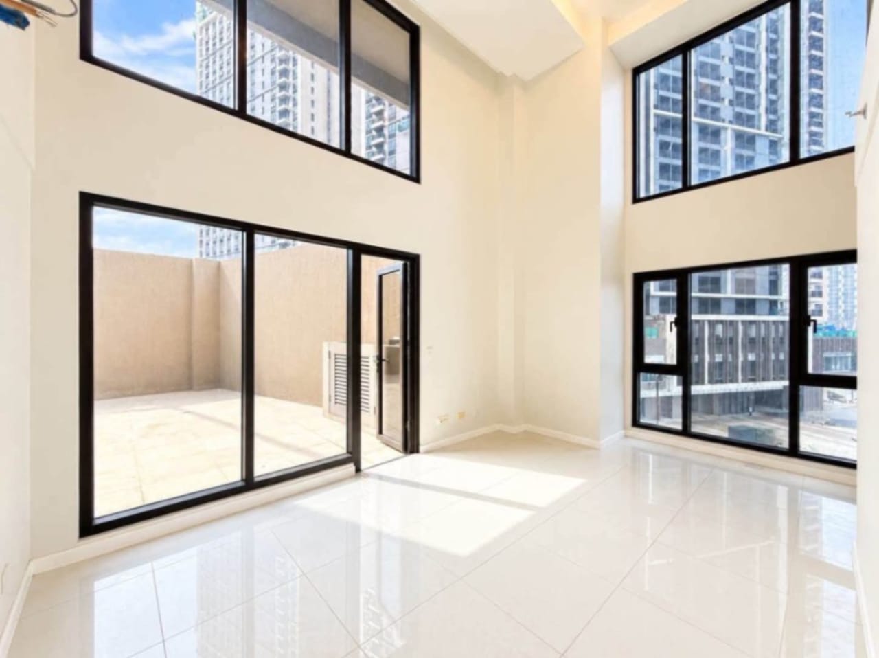 Double-height living space with upper mezzanine in a 2-bedroom loft condo at Mandani Bay Tower 2