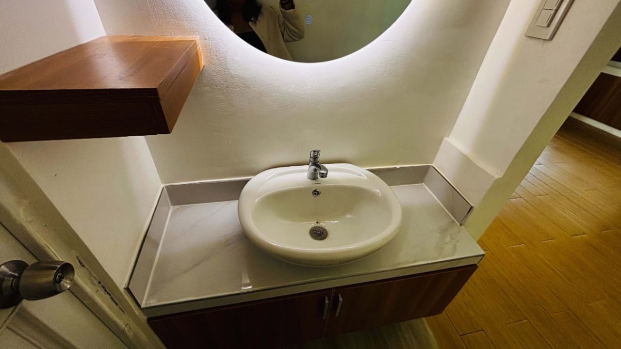 Modern bathroom vanity with round mirror, white countertop basin, and wooden shelving in a bungalow at St. Joseph Heights Subdivision, Yati.