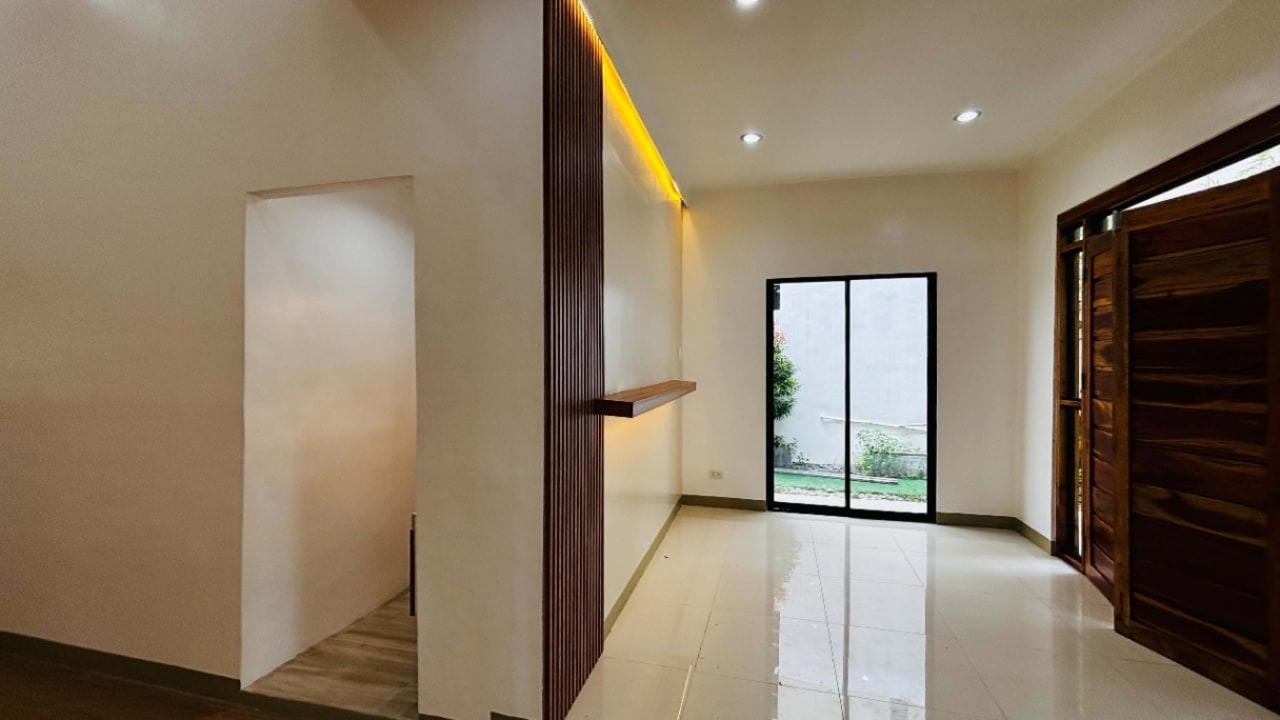 Open living space with sliding glass doors, polished flooring, and modern recessed lighting in a tropical bungalow in Yati, Liloan.