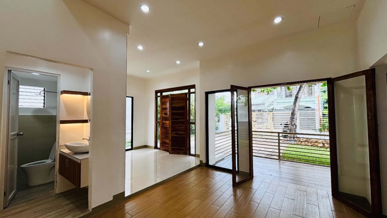 Bright living and dining area with floor-to-ceiling sliding glass doors and an open layout in a modern tropical house for sale in Liloan, Cebu.