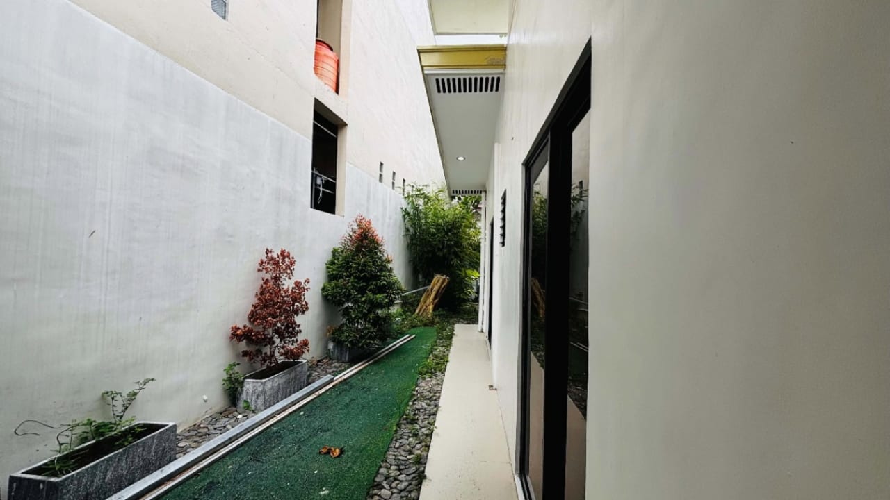Narrow outdoor side passage with white walls, decorative plants, and tiled flooring at a modern tropical bungalow in Liloan, Cebu.