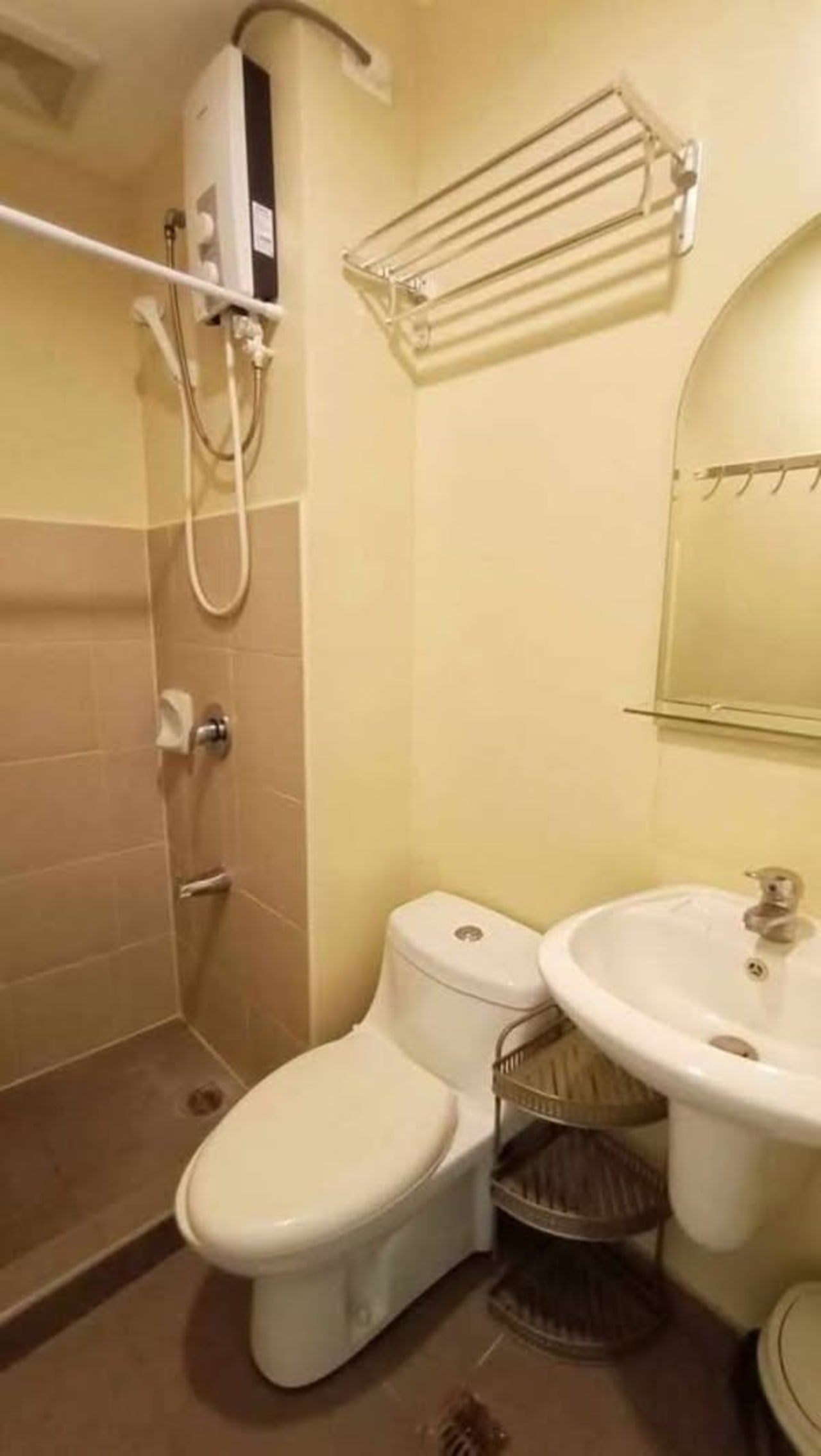 Compact bathroom with toilet, pedestal sink, wall-mounted water heater, and shower area in a studio condo at Avida Riala Tower 3, Cebu.