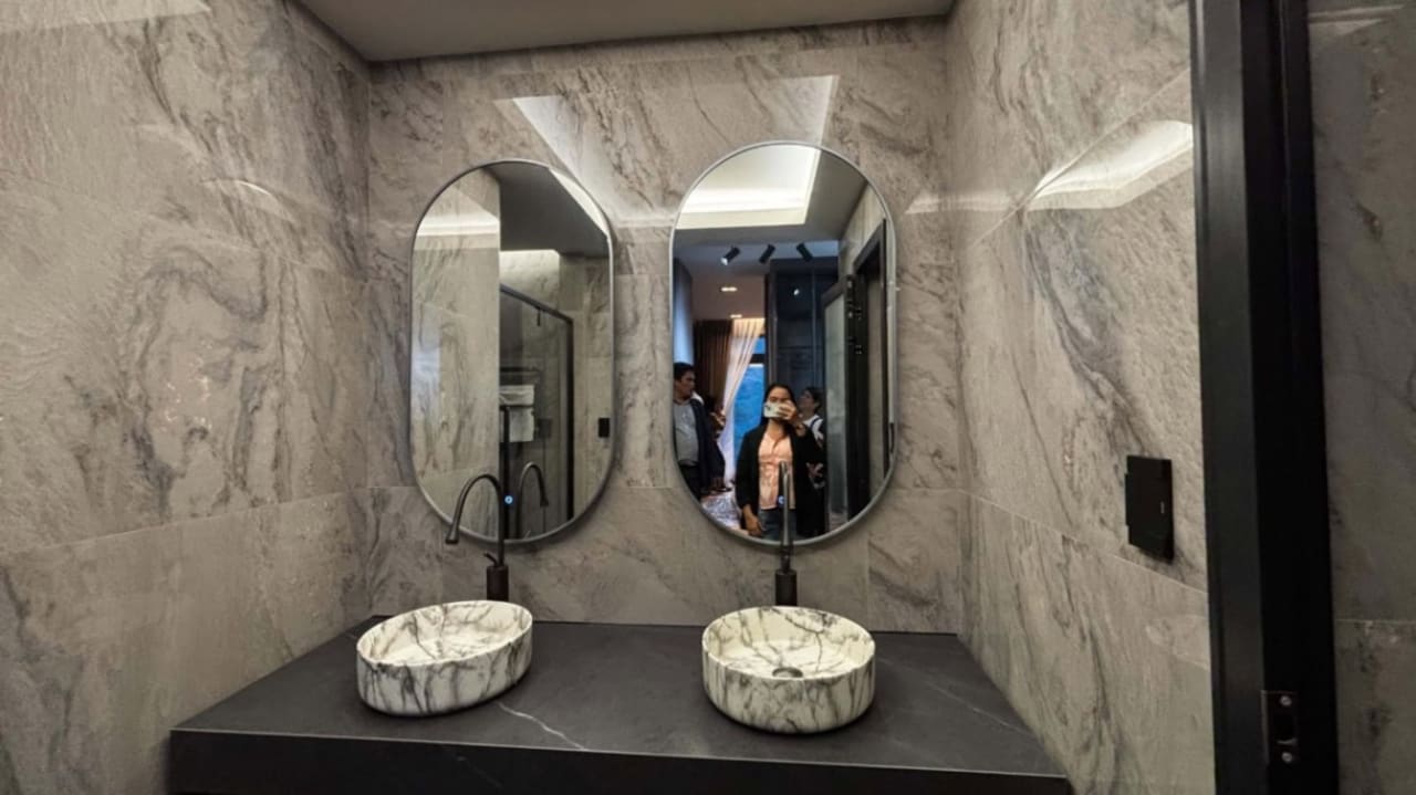 Double-sink bathroom vanity with round mirrors, stone countertop, and decorative lighting in a contemporary three-storey house for sale in Cebu City.