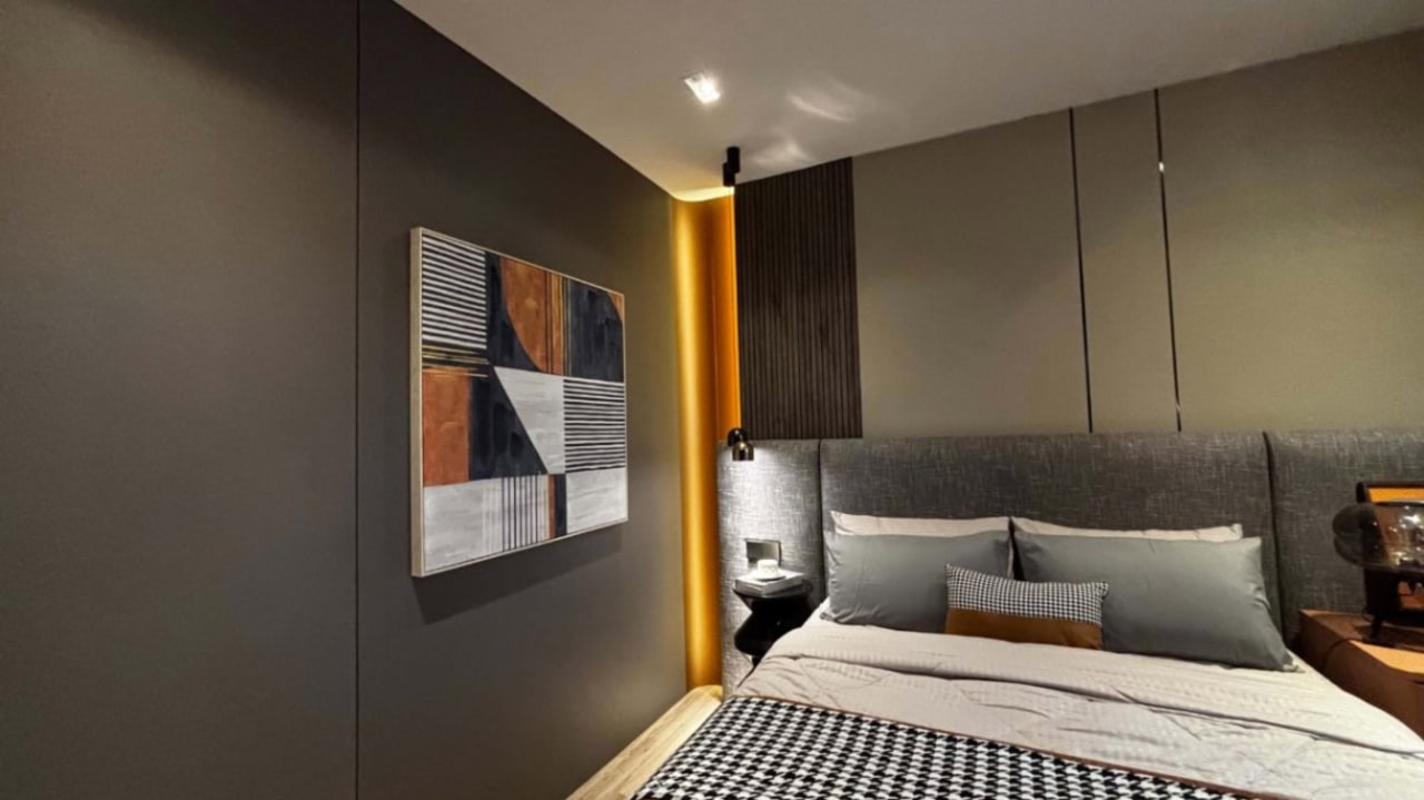 Modern bedroom with a gray upholstered bed, striped bedding, abstract wall art, and warm accent lighting in a Cebu City residential property.