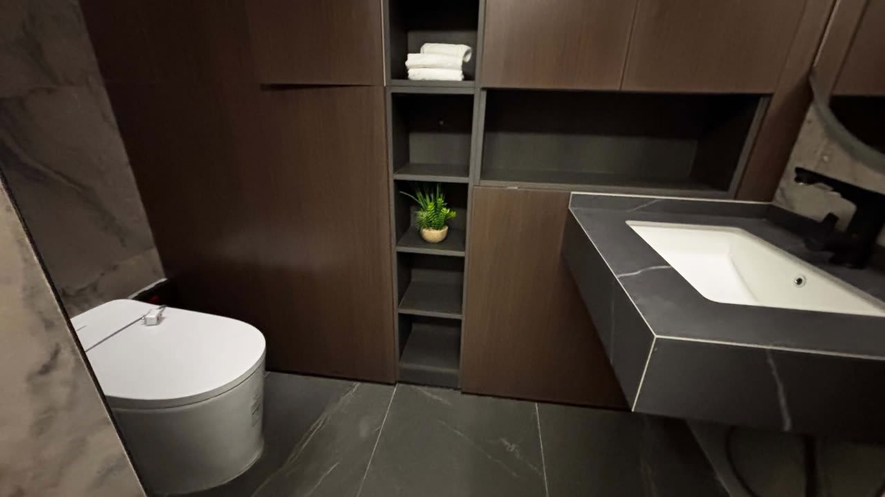 Modern bathroom with a wall-mounted toilet, white countertop basin, dark cabinetry, and built-in shelving in a three-storey house for sale in Cebu City.
