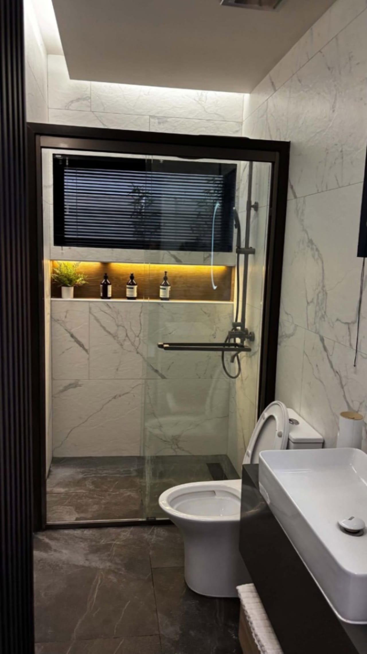 Bathroom with a glass-enclosed shower, wall-mounted shower fixtures, white toilet, and floating vanity in a contemporary Cebu City house.
