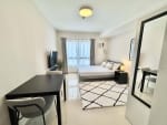 Fully furnished studio interior with bed, dining table, TV and large window at JTower Residences Mandaue