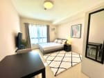 Fully furnished studio bedroom with bed, dining table, TV and large window at JTower Residences Mandaue City