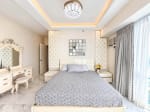 Master bedroom with tufted headboard panels, vanity dresser, crystal chandelier and tray ceiling lighting