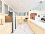 Modern kitchen with white countertops, glass-front cabinets, built-in dishwasher and double-door refrigerator