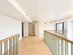 Wood-finish loft landing with metal railing in a 104 sqm 2-bedroom Mandani Bay condo